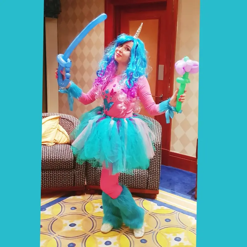 Character entertainer in a unicorn costume holding a balloon sword and a balloon flower she twisted