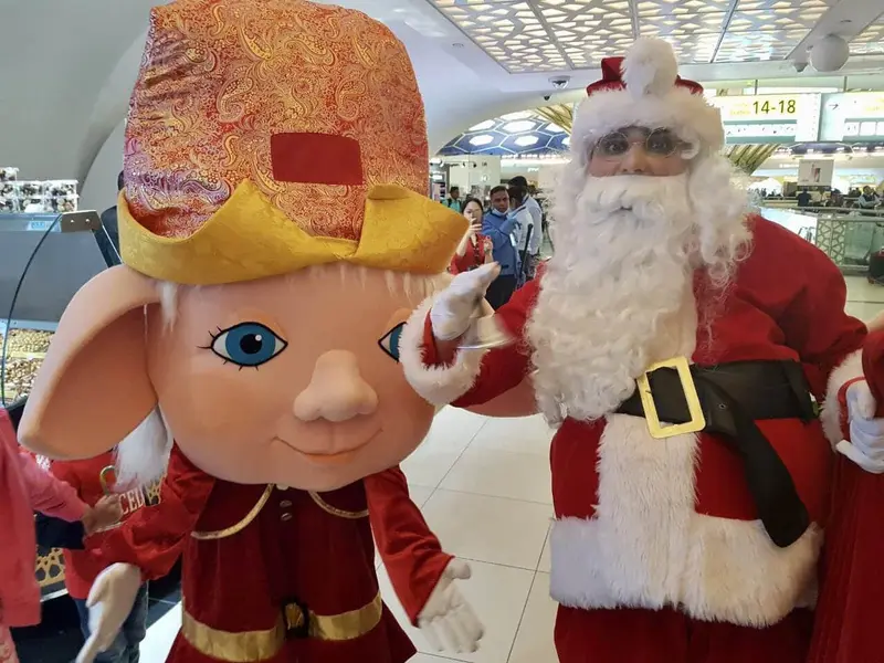 Costume mascot with a big friendly face and a Santa Claus at a festive family event in a Dubai mall