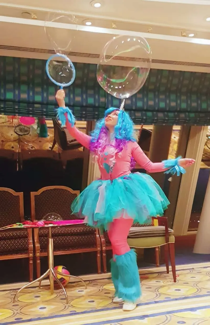 Unicorn character entertainer holding a bubble wand and a floating bubble at a kids party venue in Dubai